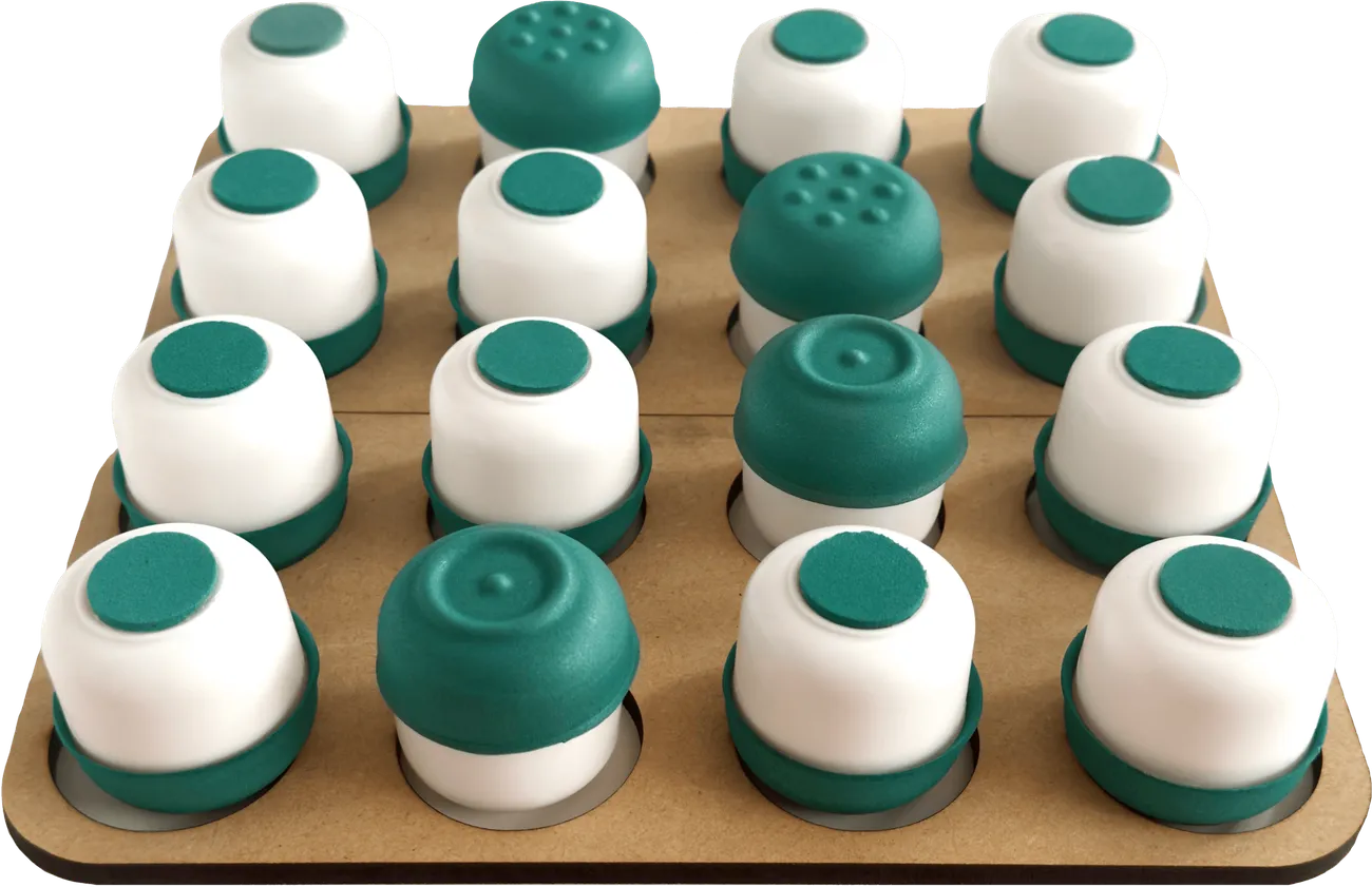 Tablero de Te Suena con 16 fichas. La imagen muestra una partida empezada. Se muestran develadas las fichas con relieve de siete puntos y las de un punto con circulo con relieve.